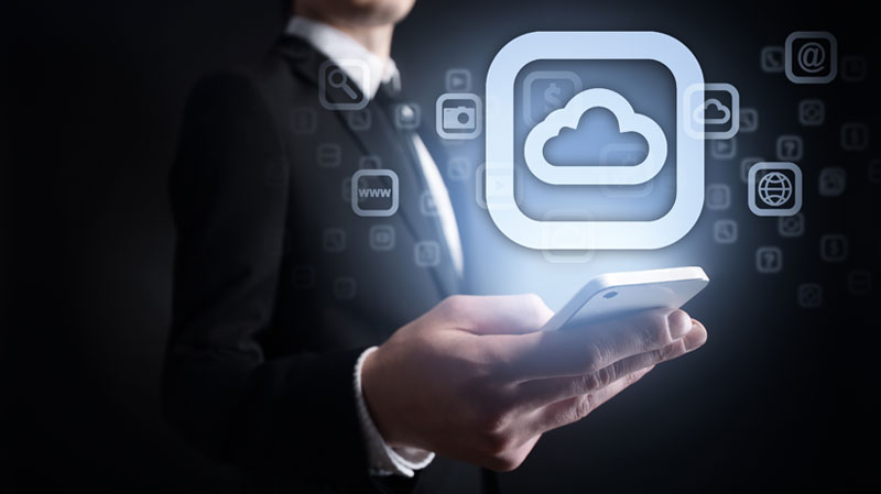 Business person holding illuminated cell phone with "cloud" icon hovering above it