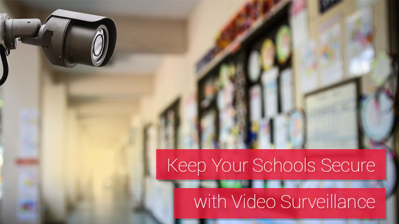 Security camera mounted in a school near a bulletin board displaying a variety of student projects.